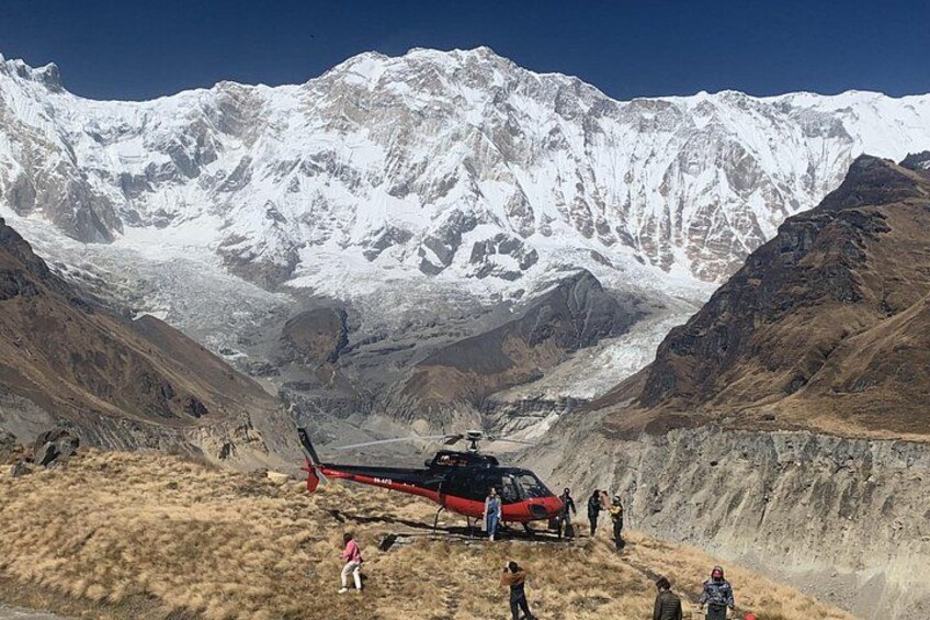 En helikopter på et bjerg med sneklædte tinder i baggrunden. 2