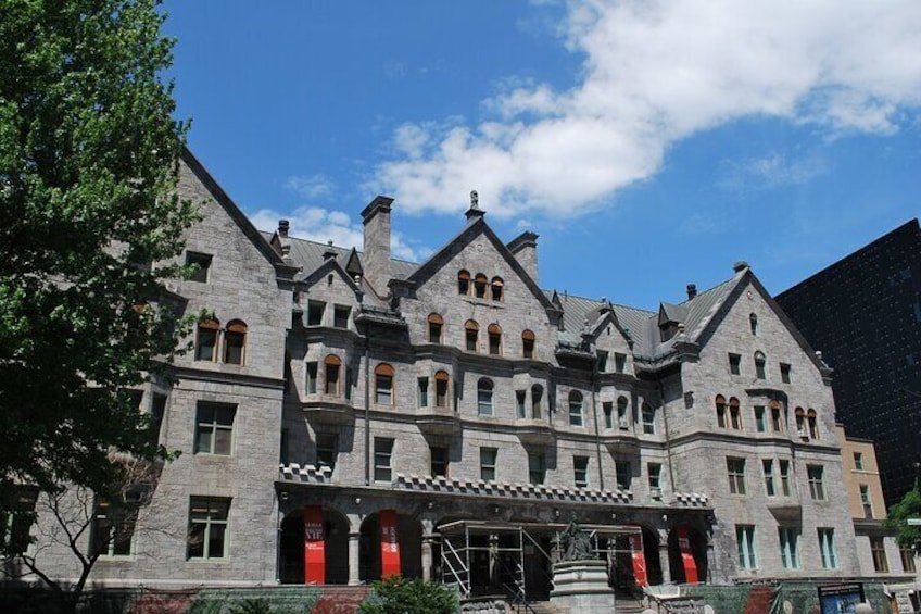A large, historic stone building with multiple windows and a prominent entrance. 5
