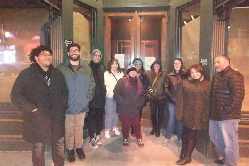 A group of people standing outside a building at night. 5