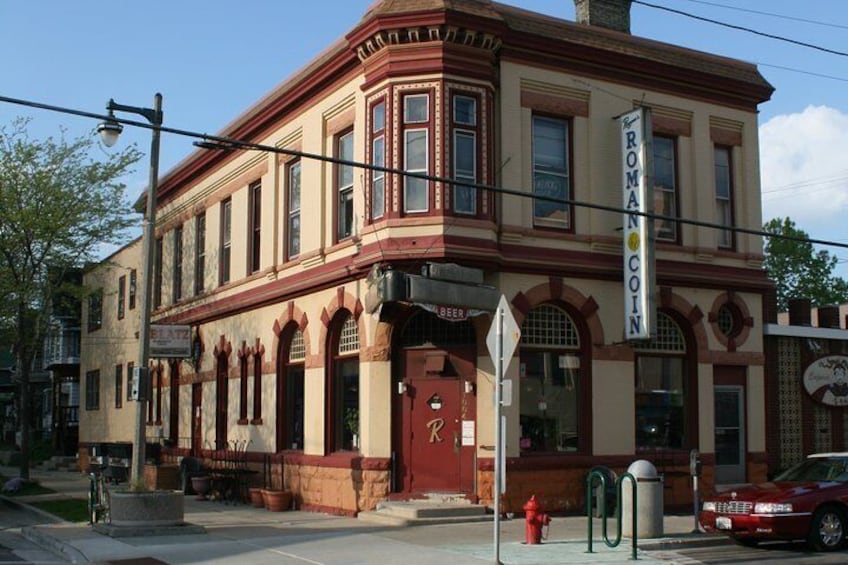 A historic building with a Roman Coin sign, a red fire hydrant, and a street lamp. 4