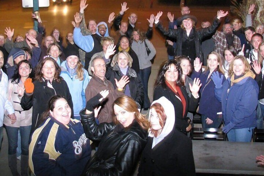A group of people outdoors, some wearing jackets, gathered closely together. 3