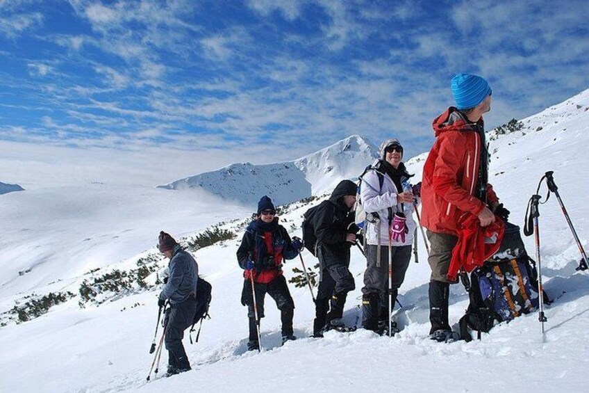 Un groupe de personnes fait une randonnée sur une montagne enneigée, sous un ciel dégagé. 2