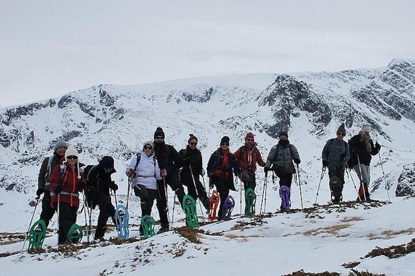 Un groupe de personnes fait une randonnée sur une montagne enneigée, équipées de raquettes. 3