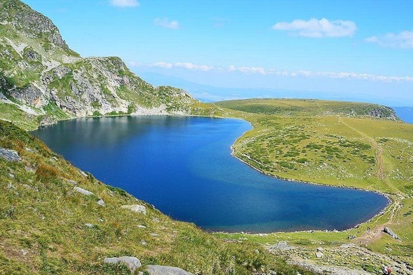 A lake surrounded by green hills and rocky terrain. 2