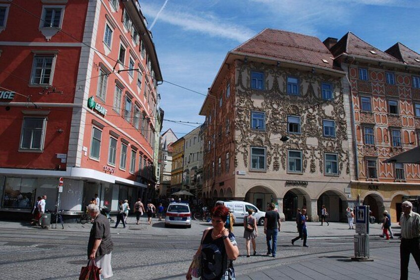 A busy urban street with pedestrians, historic buildings, and a tram. 2