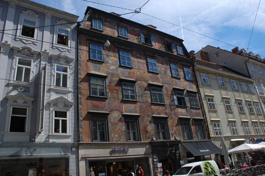 A row of multi-story buildings with various architectural styles, including ornate facades and large windows. 3