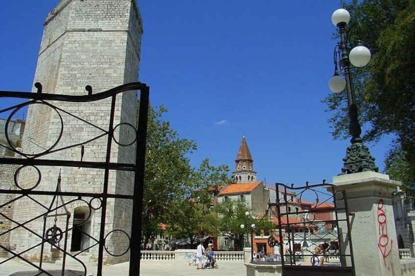 Une tour historique, une église au toit rouge et un portail en métal. 1
