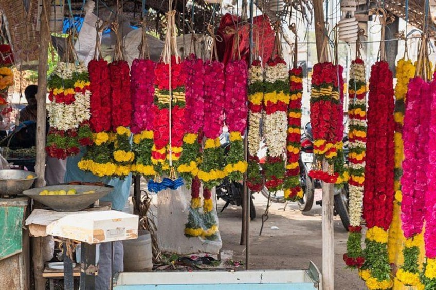 A market stall with hanging flower garlands in various colors. 2