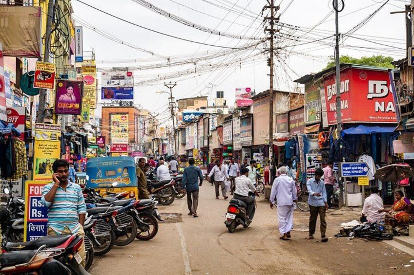 A busy street with motorcycles, pedestrians, and various shops. 3