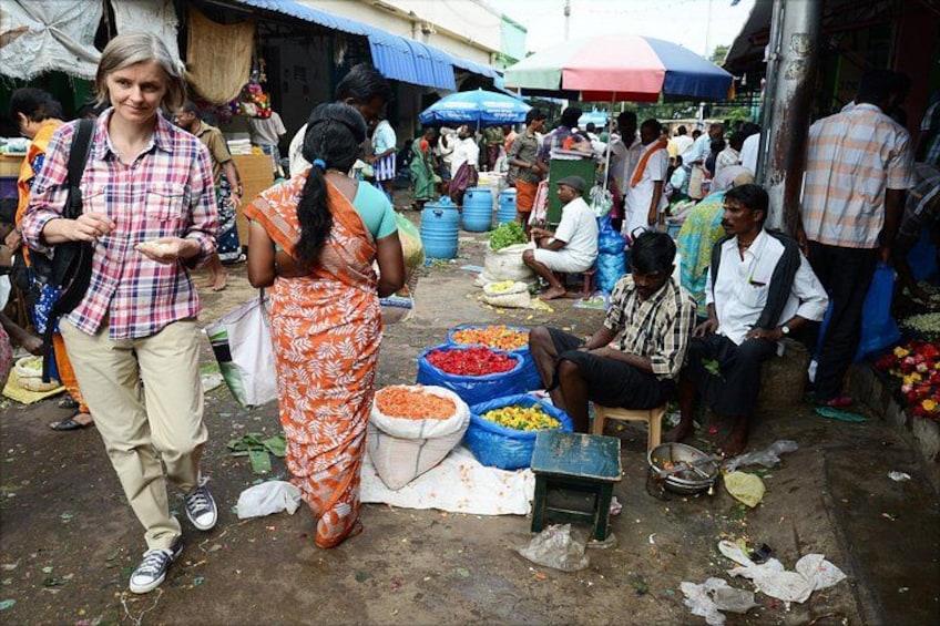 A bustling outdoor market with people shopping and vendors selling goods. 5