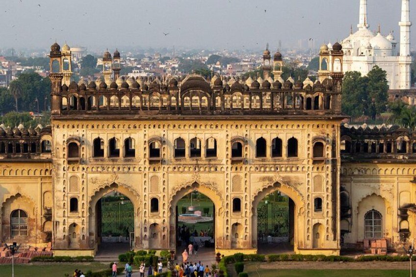 A historic building with ornate arches and domes, surrounded by a park with people. 4