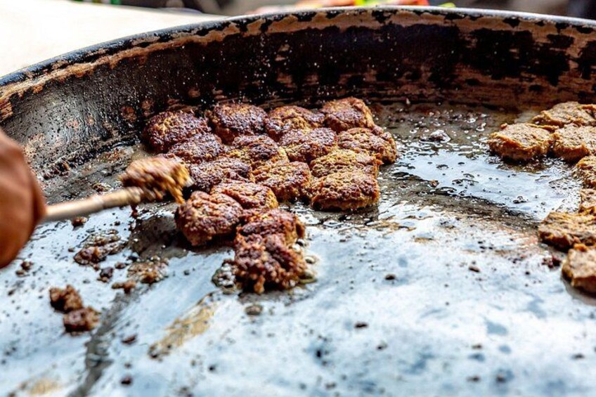 A pan with meat being cooked on a grill. 3
