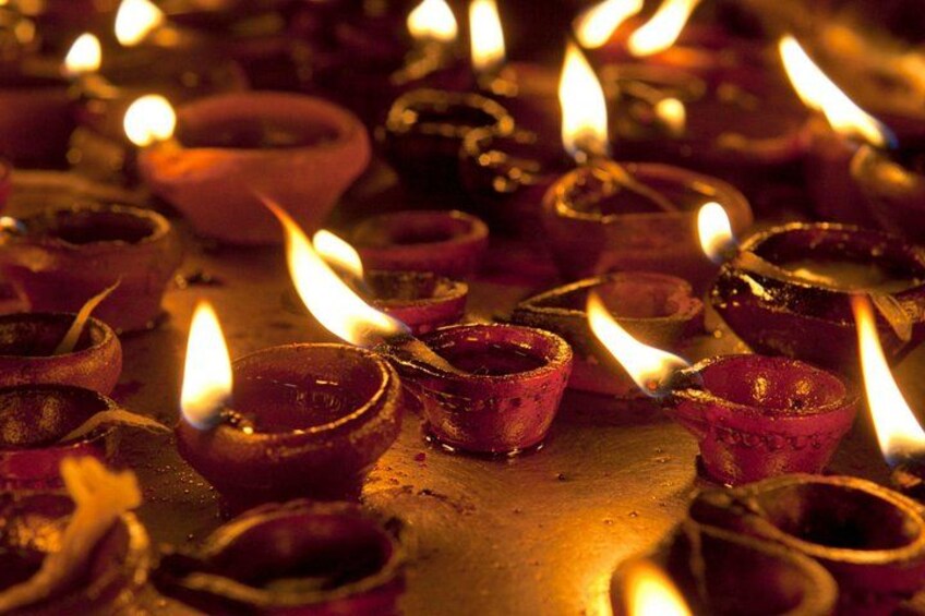 A collection of lit oil lamps on a flat surface. 5