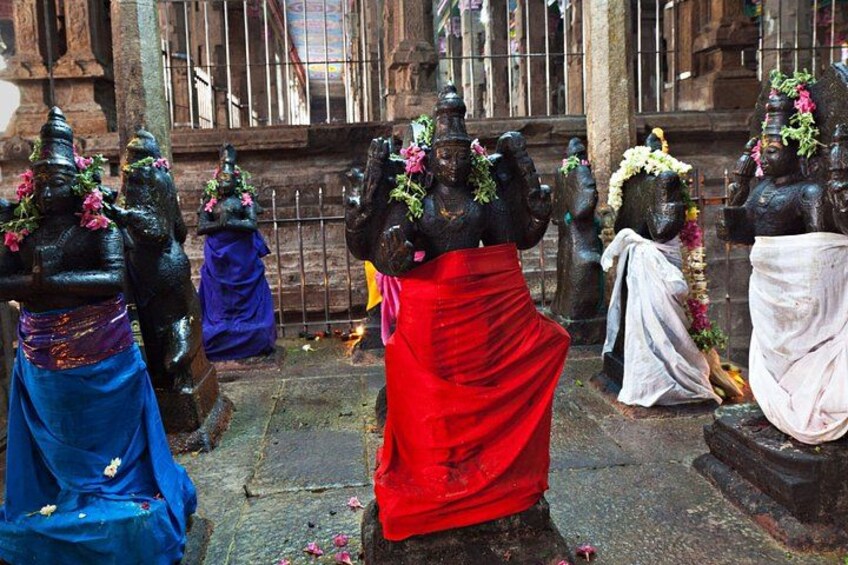 Statues of deities in traditional attire, with flowers and garlands, in an outdoor setting. 1