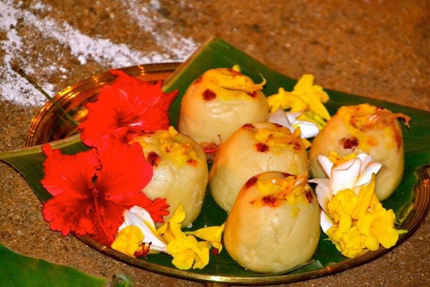 A plate of round, golden-brown sweets garnished with yellow and red flowers. 2