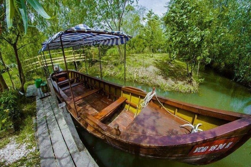 Un bote de madera amarrado a un muelle de madera, rodeado de abundante vegetación y un río tranquilo. 2