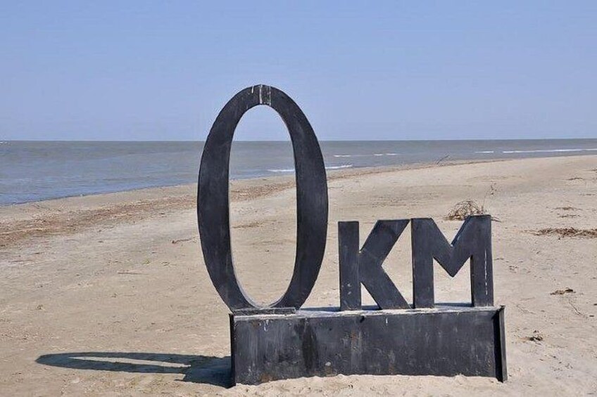 Une plaque métallique portant les lettres « KM », placée sur une plage, avec l’océan en arrière-plan. 4