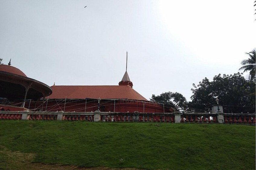 A large building with a red roof and a tall spire, surrounded by a fence and greenery. 4