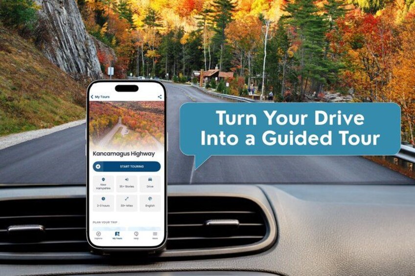 A smartphone displaying a guided tour app on a dashboard, with a scenic road and autumn foliage in the background. 1