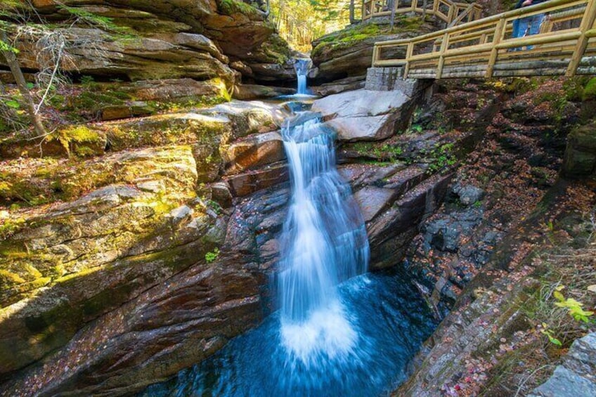 A waterfall cascading over rocks, wooden steps, and a wooden railing. 3