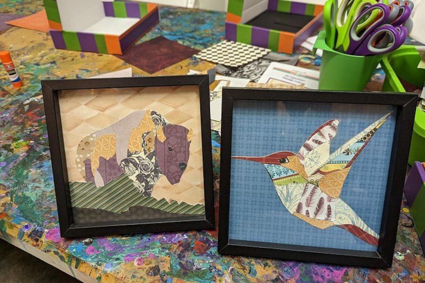 Two framed artworks on a colorful table with various craft supplies in the background. 1