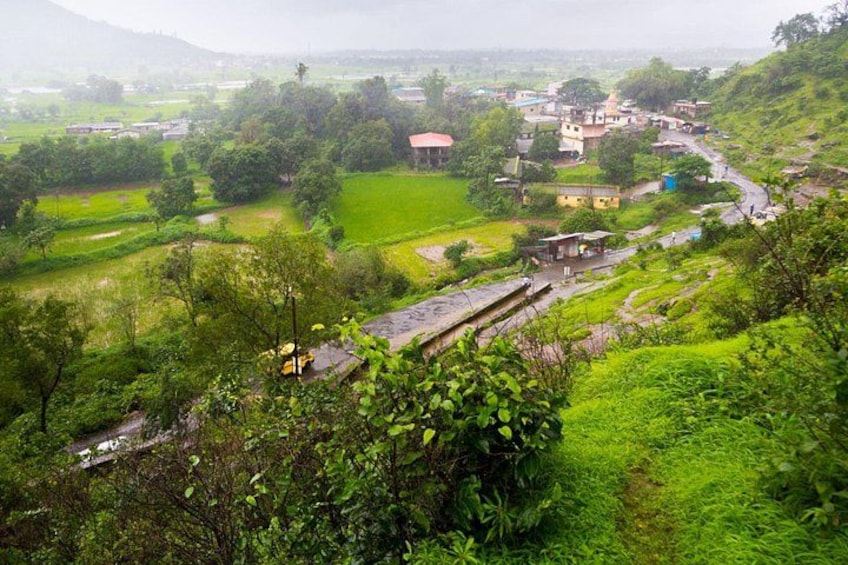 A rural landscape with terraced fields, a winding road, and scattered buildings. 2