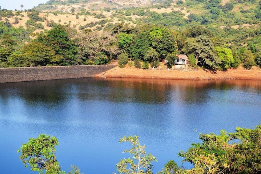 A calm lake with a small house on the shore, surrounded by trees and hills. 4