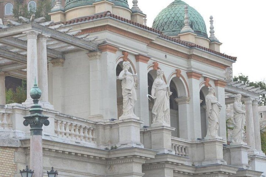 A classical building with statues, columns, and a green dome. 4