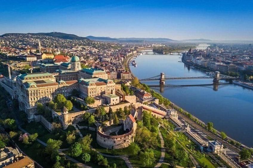 A cityscape with a prominent historical building complex, a river, and a bridge. 1