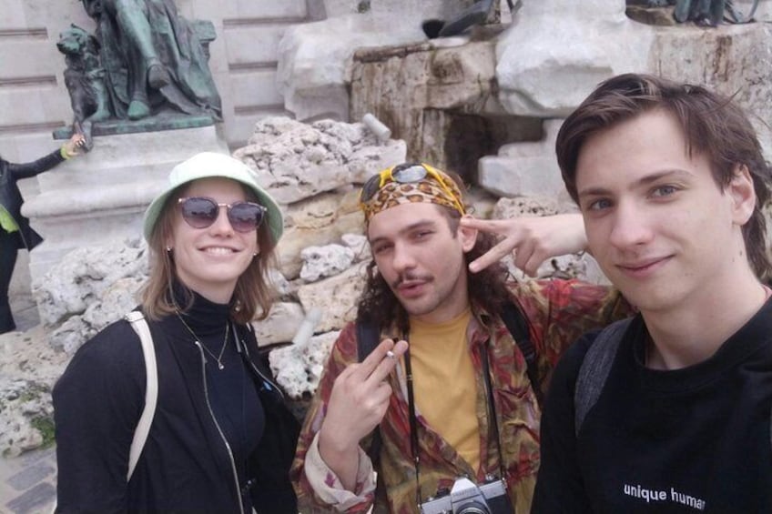 Three people posing in front of a stone structure with a statue. 3