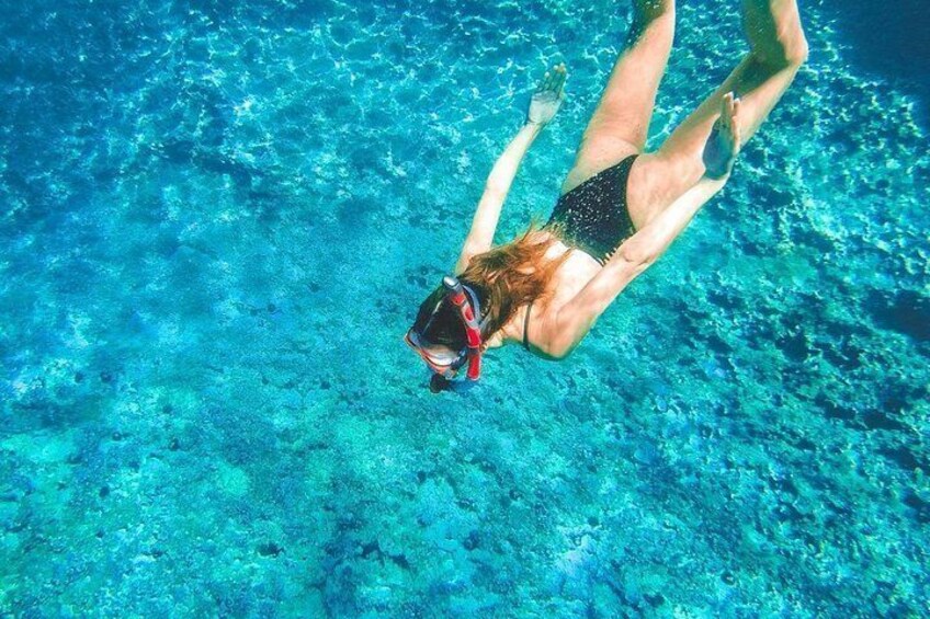 A person swimming underwater in clear blue water. 1