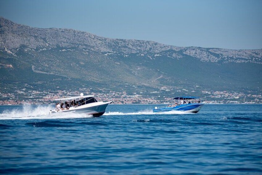 Deux bateaux sur une mer calme, avec une côte montagneuse en arrière-plan. 2