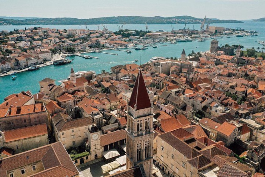 Eine Küstenstadt mit einem markanten Kirchturm, einem Hafen voller Boote und einer historischen Festung. 3