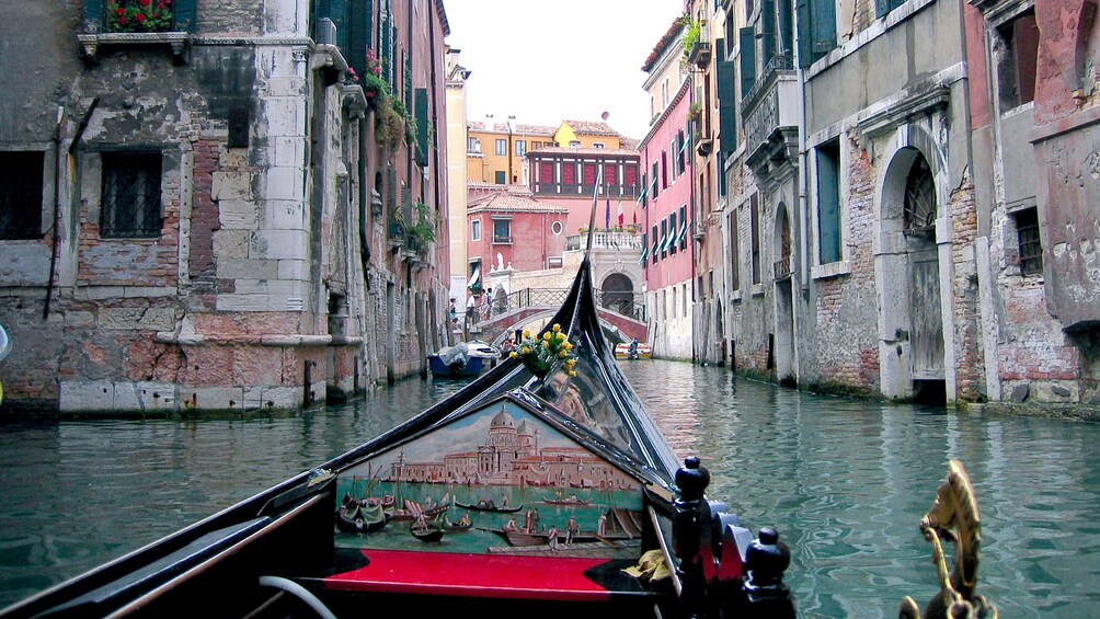 The view from the front of a gondola floating between buildings on a canal in Venice. 