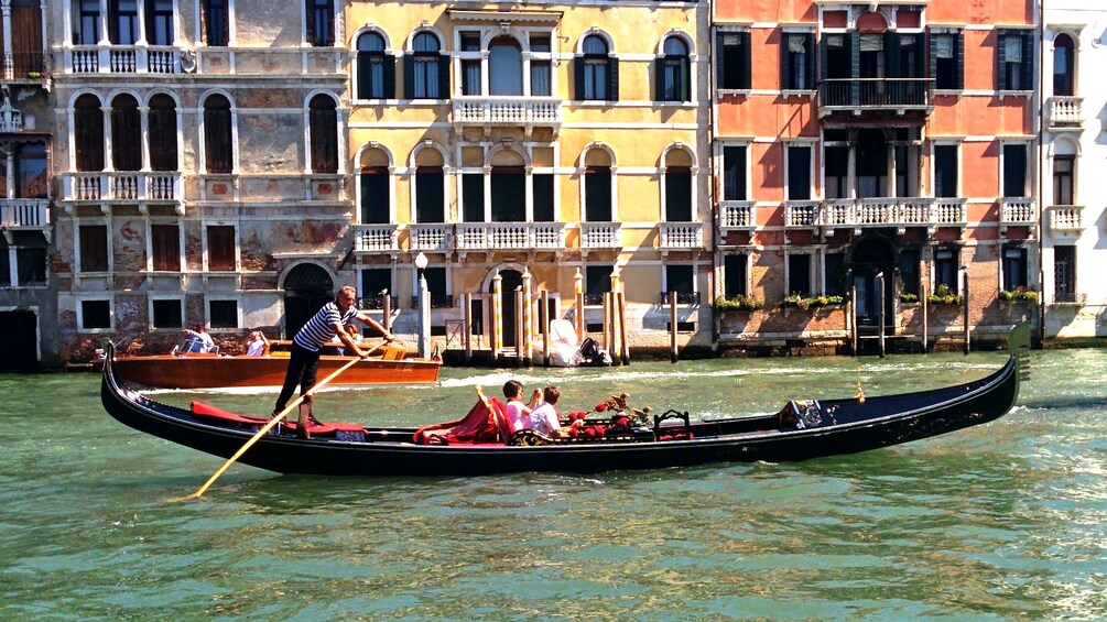 Gondola with patrons traversing through a canal in Venice