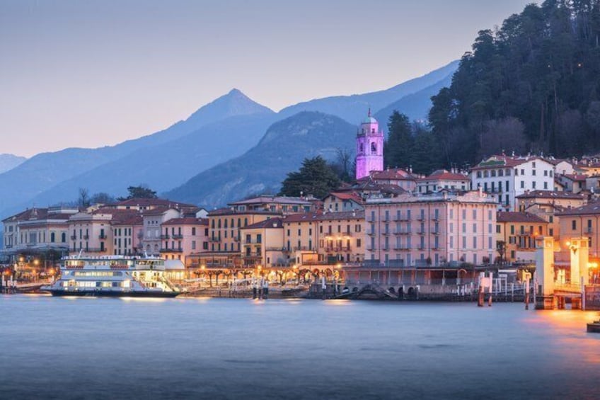 Eine Stadt am Wasser mit Gebäuden, einem markanten Turm und Bergen im Hintergrund. 3