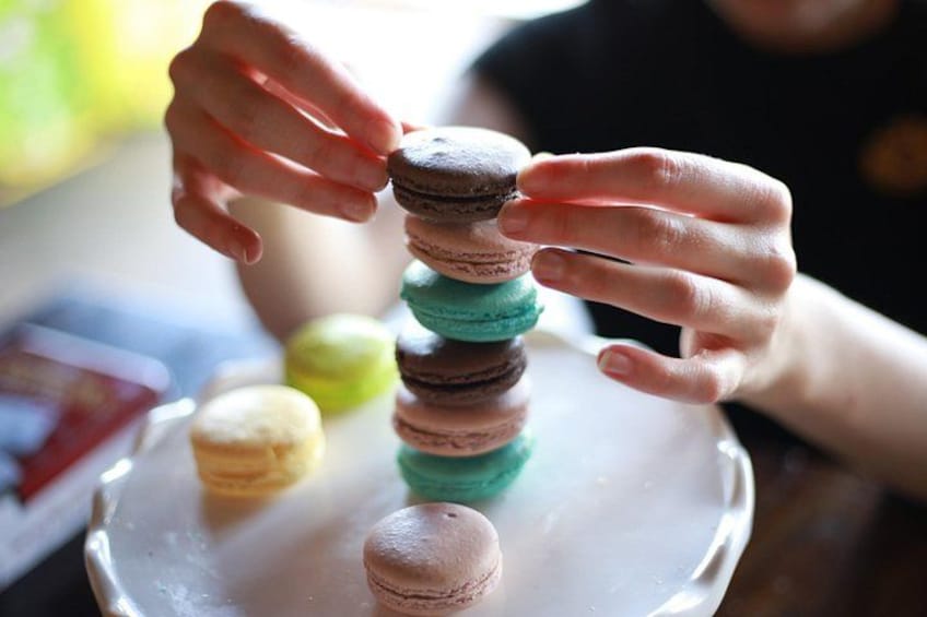 Hände stapeln Macarons auf einem Teller. 2
