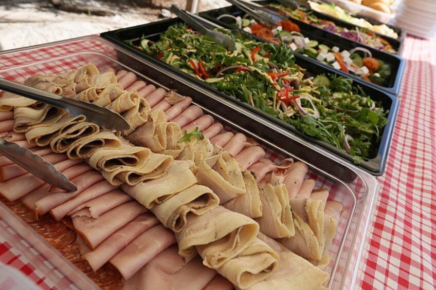 A buffet table with sliced meats and salads. 3