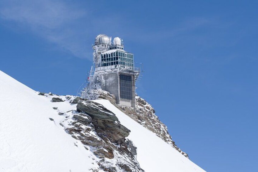 A snow-covered mountain with a large observatory or research facility on top. 1