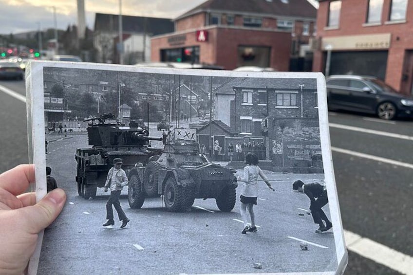 A black and white photo of a street scene with a military vehicle and people. 4