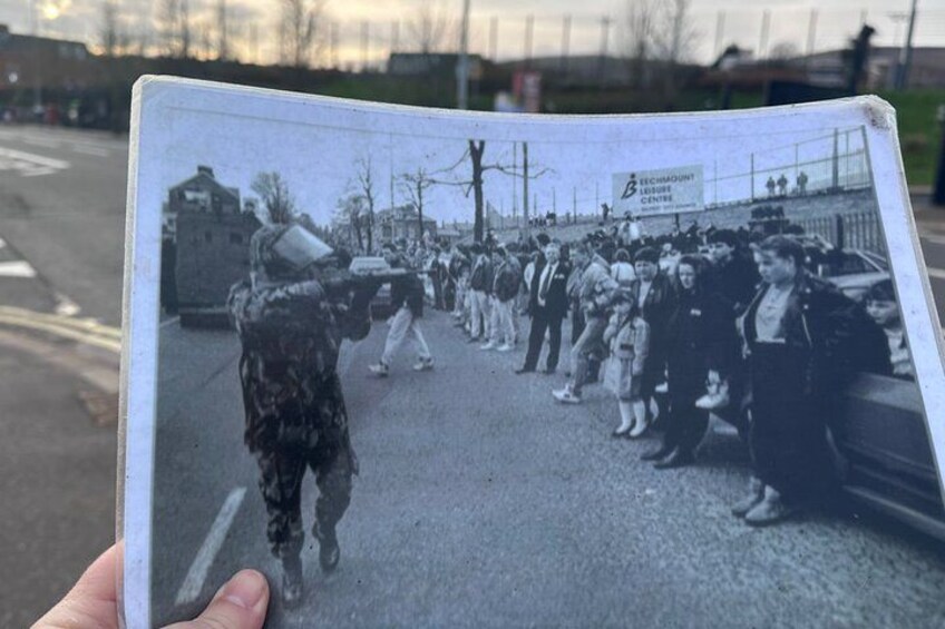 A group of people walking on a street, a signboard, and a building in the background. 5