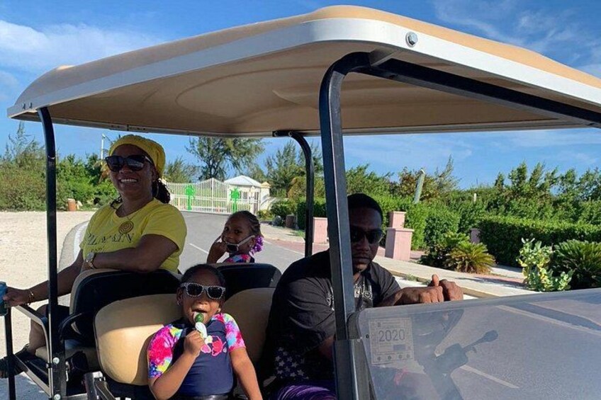 A golf cart with four people, including a child, on a sunny day. 1