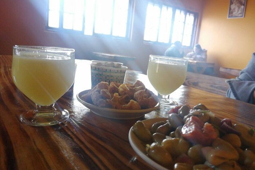 Une table en bois avec deux verres de jus d’orange, une assiette de croissants et un bol d’olives. 3