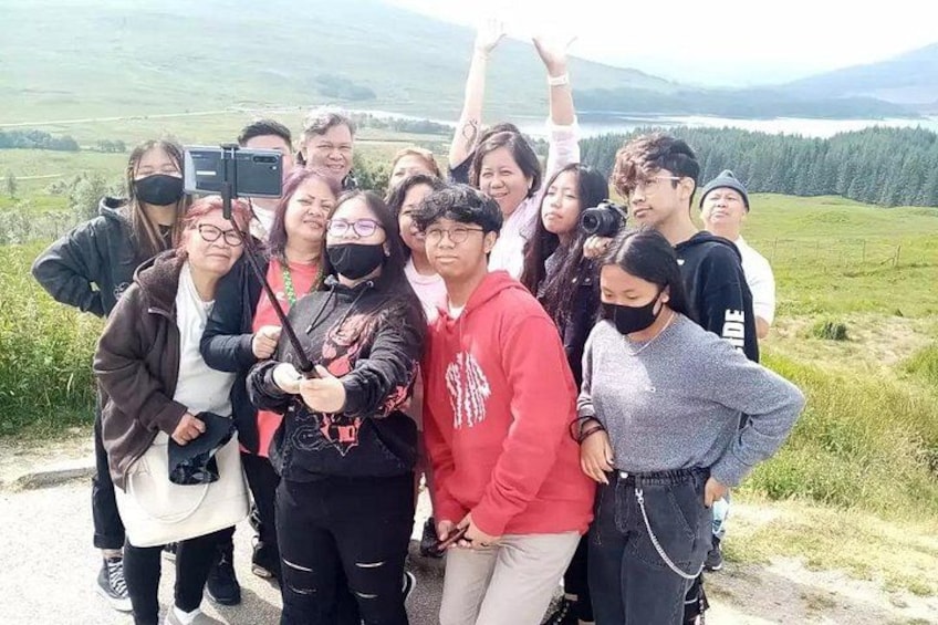 A group of people posing for a selfie in a mountainous area with a clear sky. 3