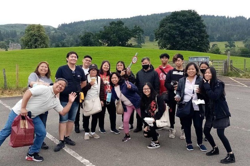 A group of people posing on a road with a green field and hills in the background. 1