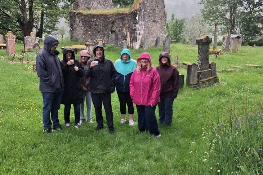 A group of people standing in a grassy area with a stone structure in the background. 2