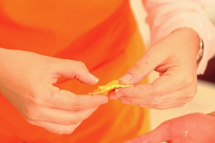Hands holding a piece of yellow fruit, possibly a lemon, with a blurred orange background. 2