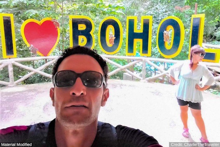 A person in the foreground with a sign in the background that reads 'I ♥ B OHOL'. 4
