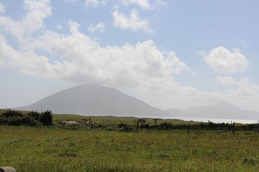 A grassy field with a mountain in the background and a body of water to the right. 4