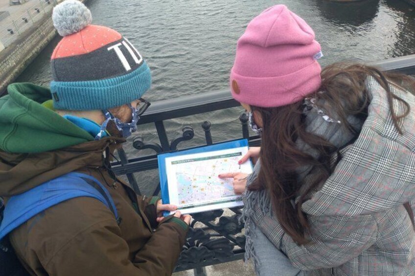 Two people examining a map on a bench by a body of water. 2